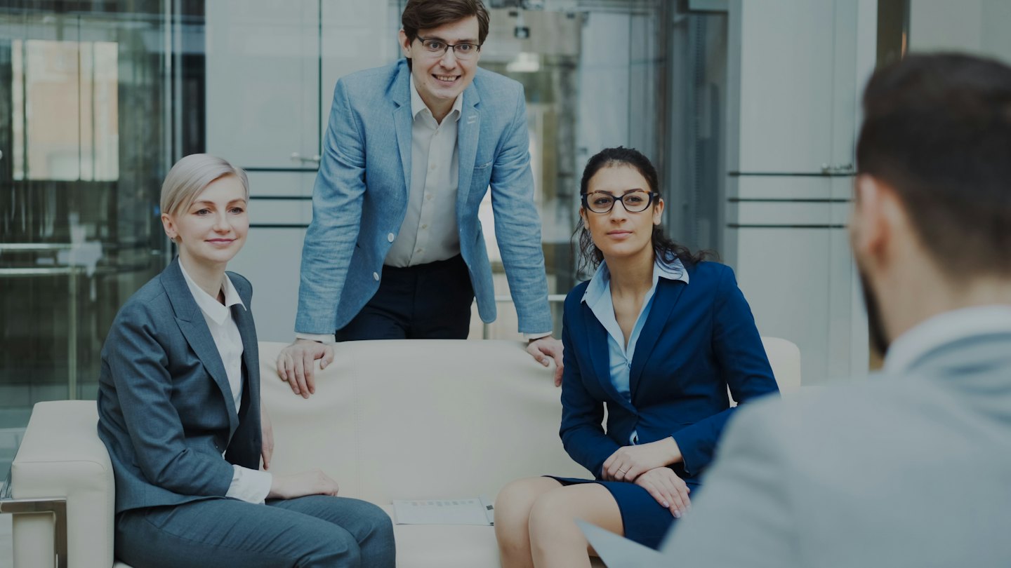 Business team discusses ideas in a modern office lobby.